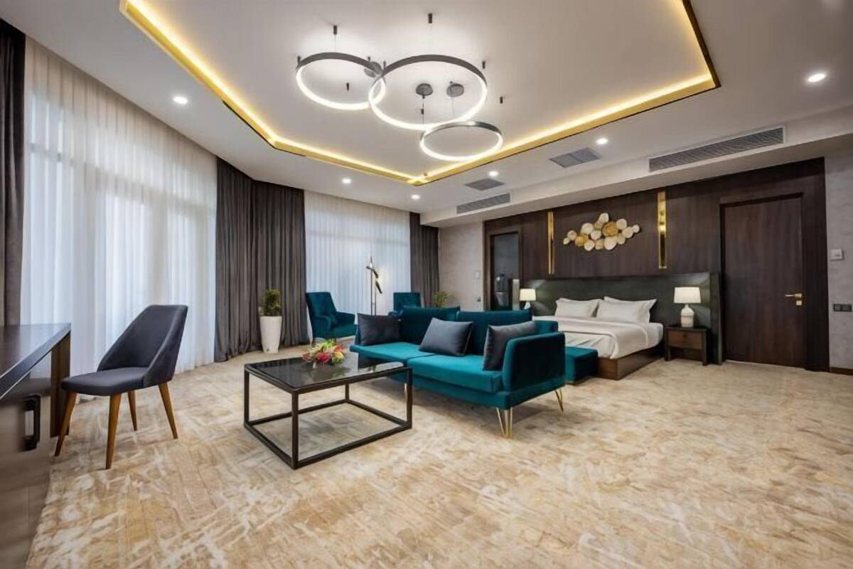 A modern hotel room with a sofa, a coffee table, a bed, and a nightstand.