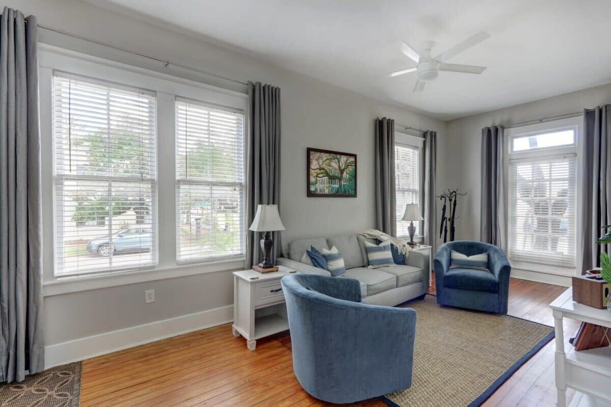 Un salon comprenant un canapé, deux fauteuils, une table d’appoint et un ventilateur de plafond.