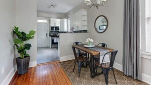A dining area with a wooden table, black chairs, a chandelier, and a potted plant.