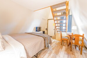 Une chambre à coucher avec un lit, un bureau, une chaise et un escalier en bois.