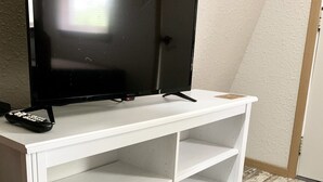 Un mueble blanco para televisión con un televisor de pantalla plana y un control remoto.