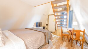 Un dormitorio con cama, escritorio, silla y escalera de madera.
