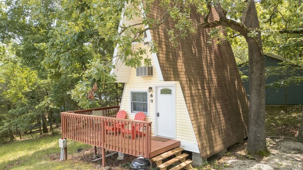 Ett litet hus med en veranda, en grill och ett trädäck.
