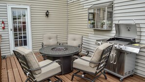 Un patio con una mesa redonda, cuatro sillas y una parrilla.