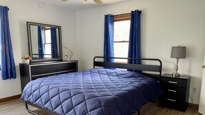Un dormitorio con cama, cómoda, espejo y mesita de noche con lámpara.