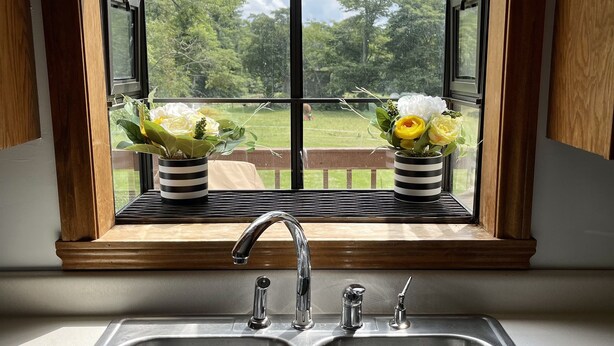 Una cocina con un lavamanos doble y una ventana que da a un jardín.