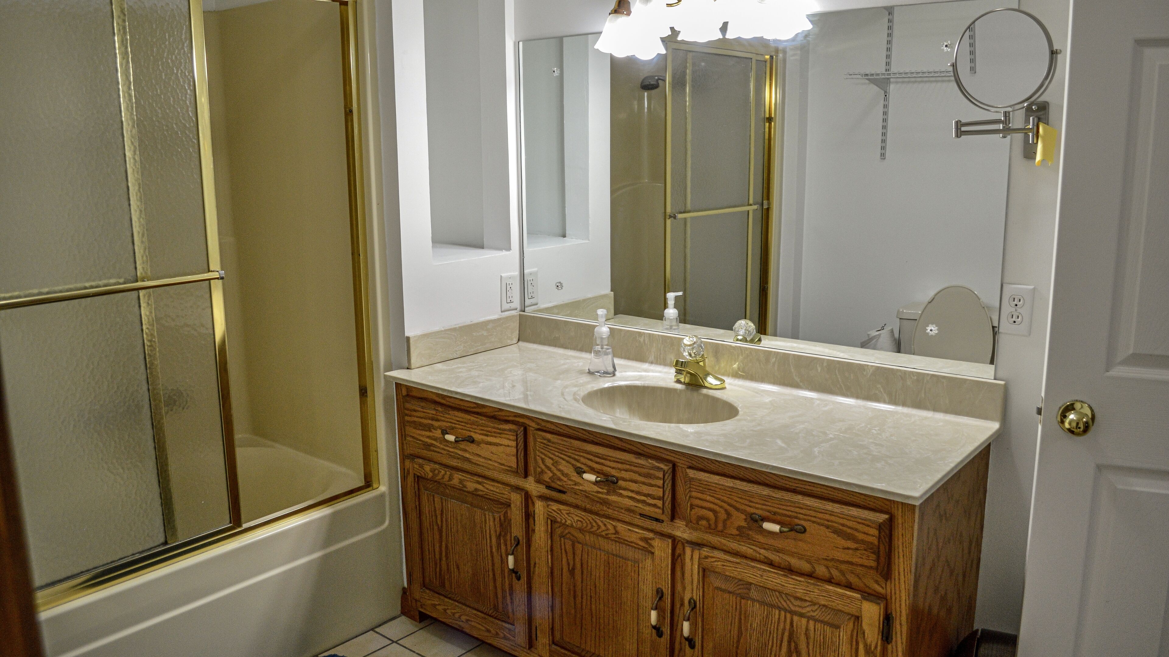 Une salle de bain avec un meuble-lavabo en bois, un évier, un miroir et une cabine de douche.