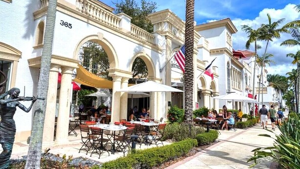 A building with a number '365' on the facade, outdoor seating with umbrellas, and palm trees. - Romantic vacation spot by the water with private heated pool and spa, kayaks! (Cape Coral)
