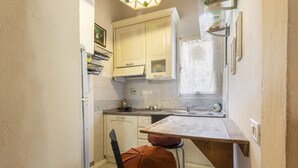 A compact kitchen with white cabinets, a wooden countertop, and a window with a curtain. - Pinocchio by Mmega (Florence)