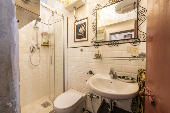 Une salle de bain équipée d’une douche, de toilettes, d’un lavabo et d’un tableau encadré au mur.