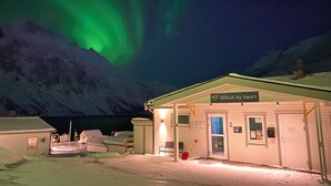A snow-covered building with a sign reading "SENJA by heart" and a red shovel outside. - Senja Fjordcamp - Senja by Heart (Torsken)
