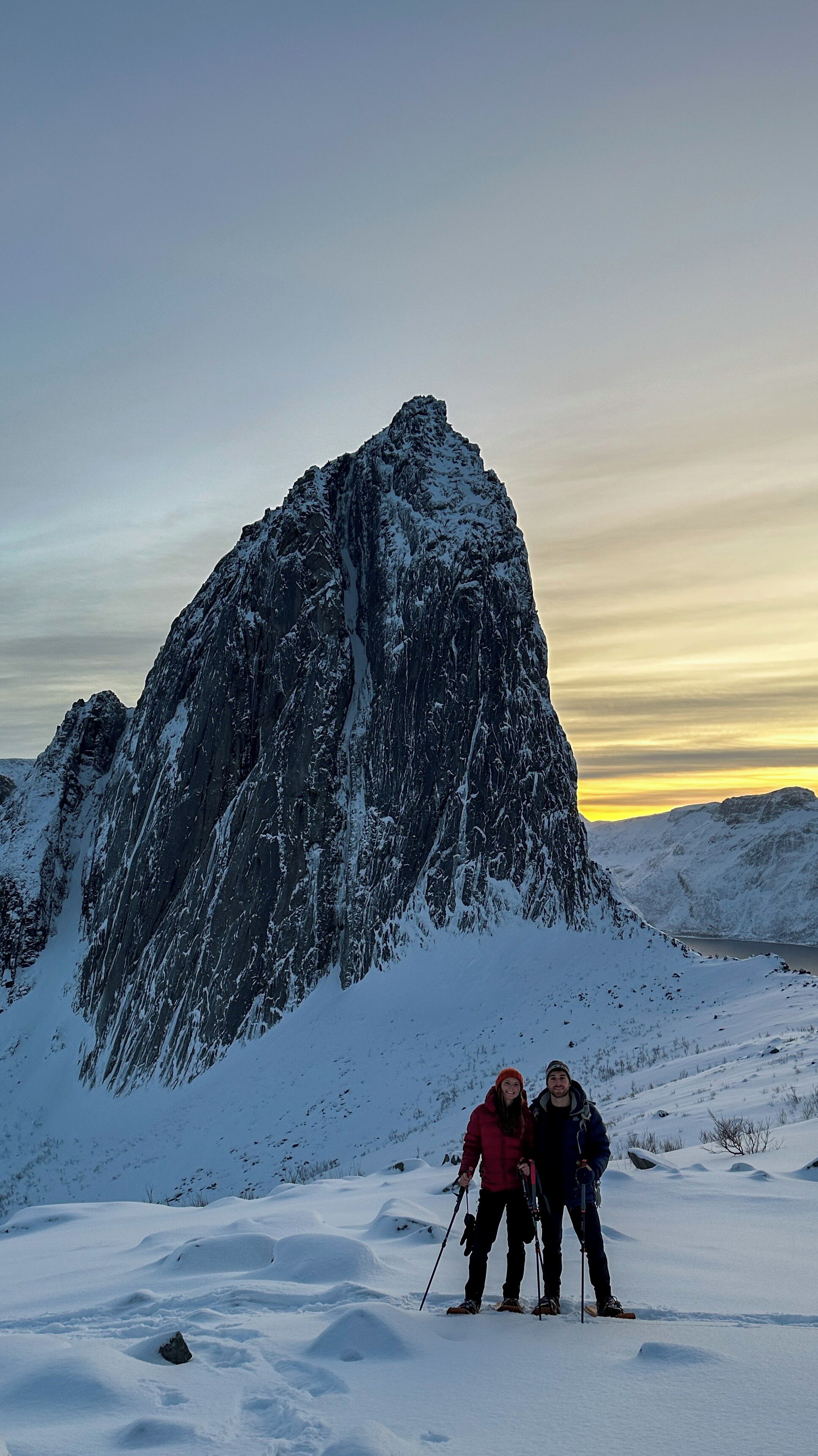 A snow-covered mountain with two people standing in the foreground.