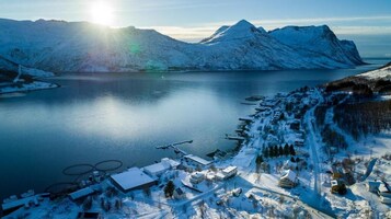 Un paisaje nevado con un lago, montañas y un pequeño poblado con edificios y muelles.