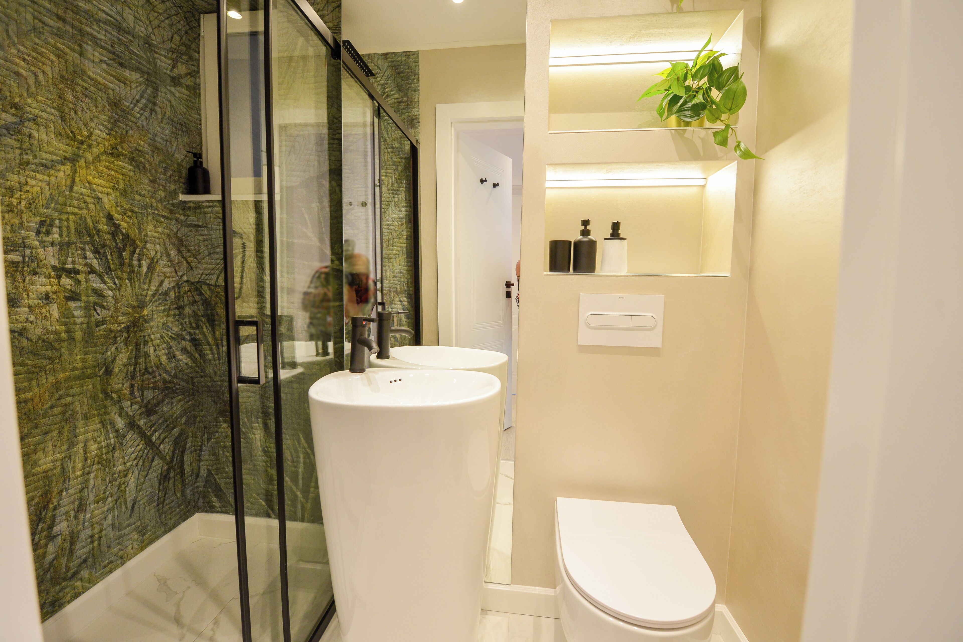 A modern bathroom with a glass shower enclosure, two white sinks, and a toilet.