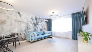 A modern living room with a sofa, coffee table, and dining area. - Celeste - One Bedroom Apartment - Next to Victoria Avenue and Cismigiu Park (Bucharest)