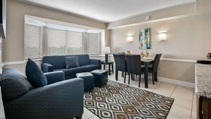 Una sala de estar con sofá, reposapiés y comedor con sillas y una mesa.