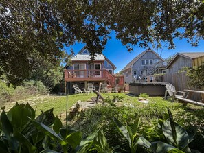 A residential backyard with a deck, outdoor seating, and a wooden structure. - SeaClusion I and SeaClusion II: Centrally located, perfect for biking or walking (Ocracoke)