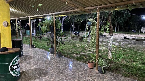 Eine Außenpatio-Terrasse mit Fliesenboden, Pflanzkübeln und einem überdachten Bereich mit einer gelben Säule.