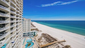 Un hotel moderno de gran altura con múltiples balcones con vistas a una playa y al océano.