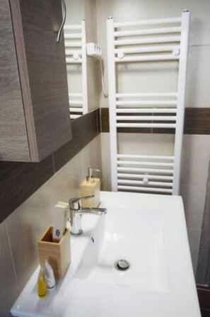 A modern bathroom with a white sink, wooden soap holder, and a towel rack.
