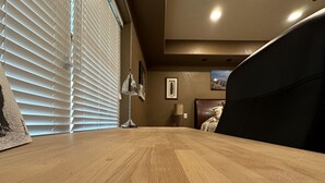 Une table de salle à manger en bois se trouve dans une pièce où il y a un lit, une lampe et un tableau au mur.