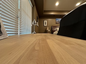 Cozy retreat with a dining table, lamp, and comfortable bed, featuring a window with blinds and a ceiling light.