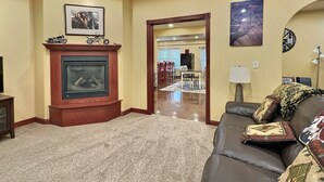 Un salon avec une cheminée, un canapé et, au fond, un coin repas.