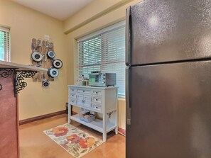 Compact kitchen with refrigerator, microwave, and storage cabinet.