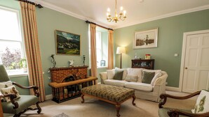 A traditional living room with a fireplace, a sofa set, a wooden bench, and a rug. - Fordie South Cottage (Crieff)