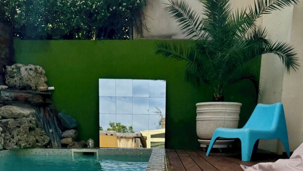 A swimming pool with a tiled edge, a wooden deck, a blue chair, and a potted plant. - Nice town house, 4 mn from Bordeaux Rive droite Private swimming pool (Cenon)
