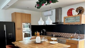 A modern kitchen with a wooden island, bar stools, and a hanging light fixture. - Nice town house, 4 mn from Bordeaux Rive droite Private swimming pool (Cenon)