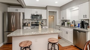 A modern kitchen with granite countertops, stainless steel appliances, and white cabinetry. - 3BR Near Cleveland & CVNP | Sunroom + Ping-Pong (Independence)