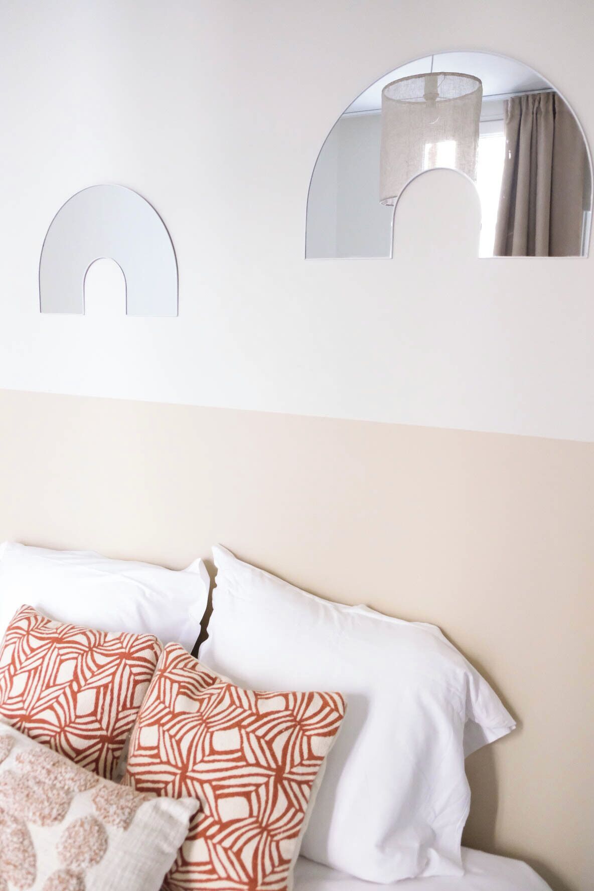 Ein Schlafzimmer mit einem Bett, Kissen und zwei Spiegeln an der Wand.
