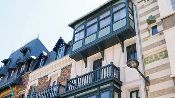 Un immeuble à plusieurs étages doté d’une grande baie vitrée et d’un balcon orné d’une balustrade verte.