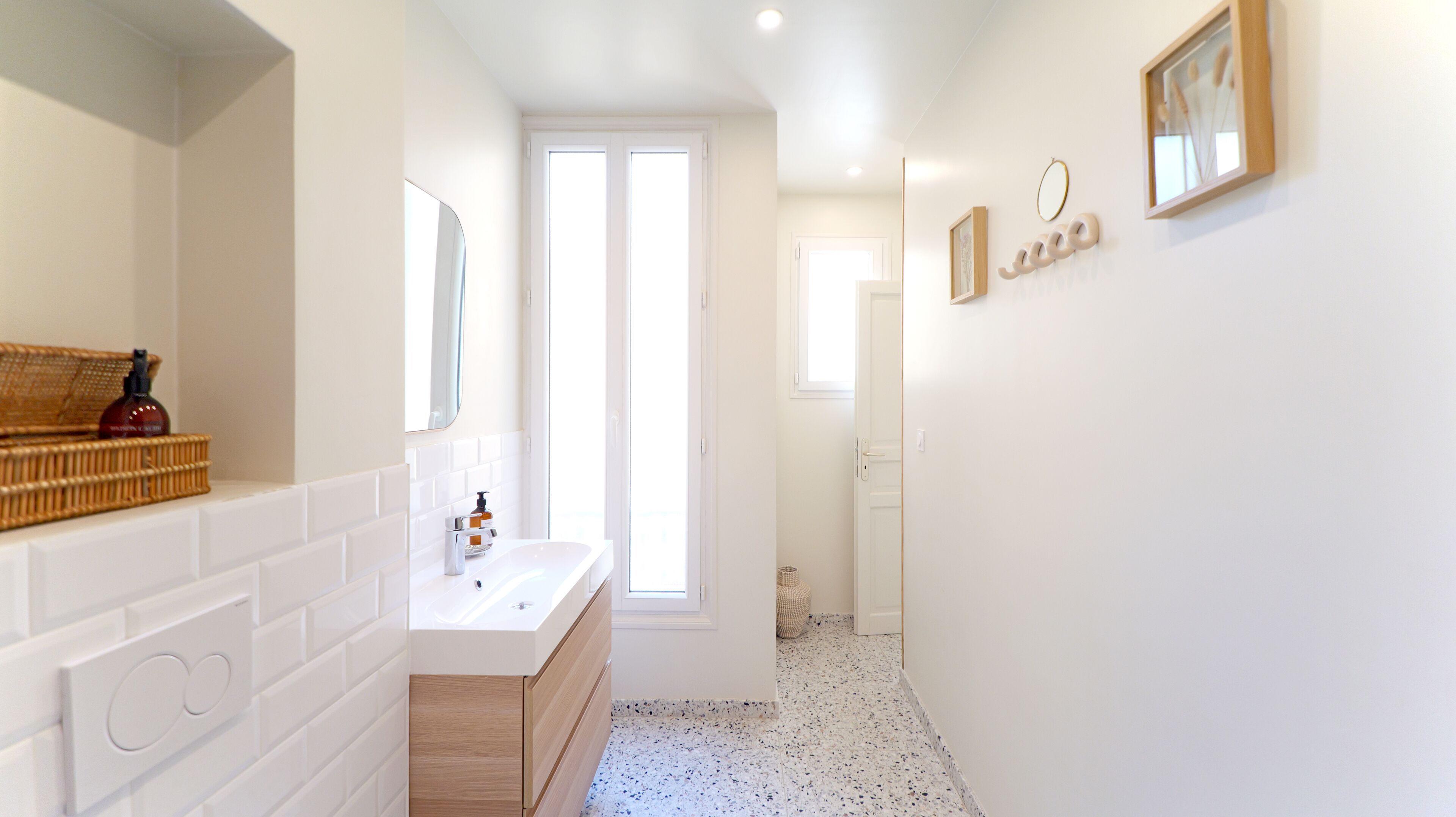 Un bagno moderno con un lavandino bianco, uno specchio e un armadietto in legno.