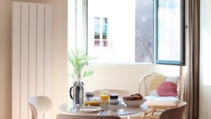 Une pièce lumineuse comprenant une table à manger, des chaises, une fenêtre et un canapé.