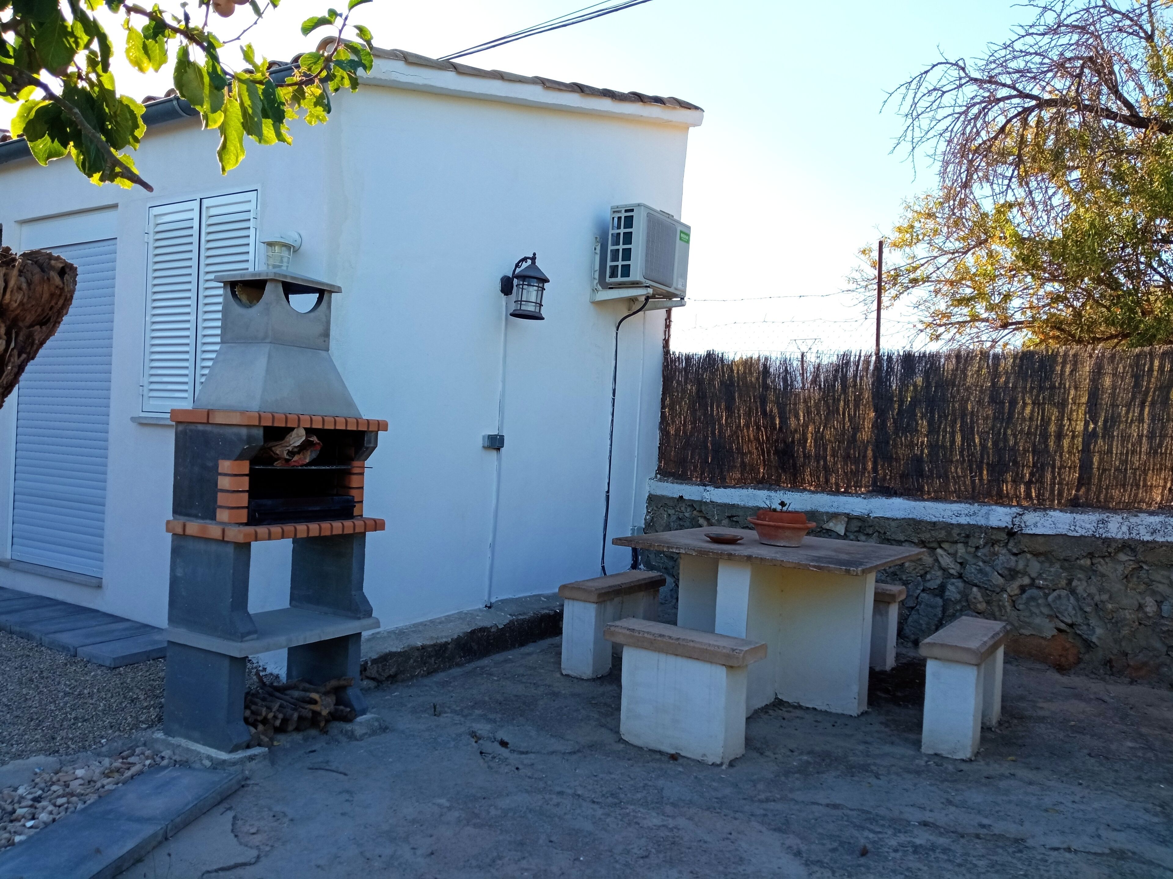 Une terrasse dotée d’un barbecue intégré, d’une petite table et d’une plante en pot.