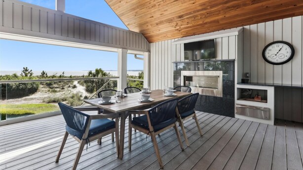 Eine Terrasse mit Holztisch und -stühlen, einem eingebauten Grill und einer Uhr an der Wand.