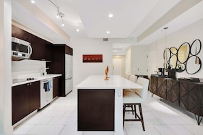 A modern kitchen with a central island, dark cabinetry, and white countertops. - Villa Vista by VIAC - 2 Story w/ 3Bdrms & Golf View (Doral)