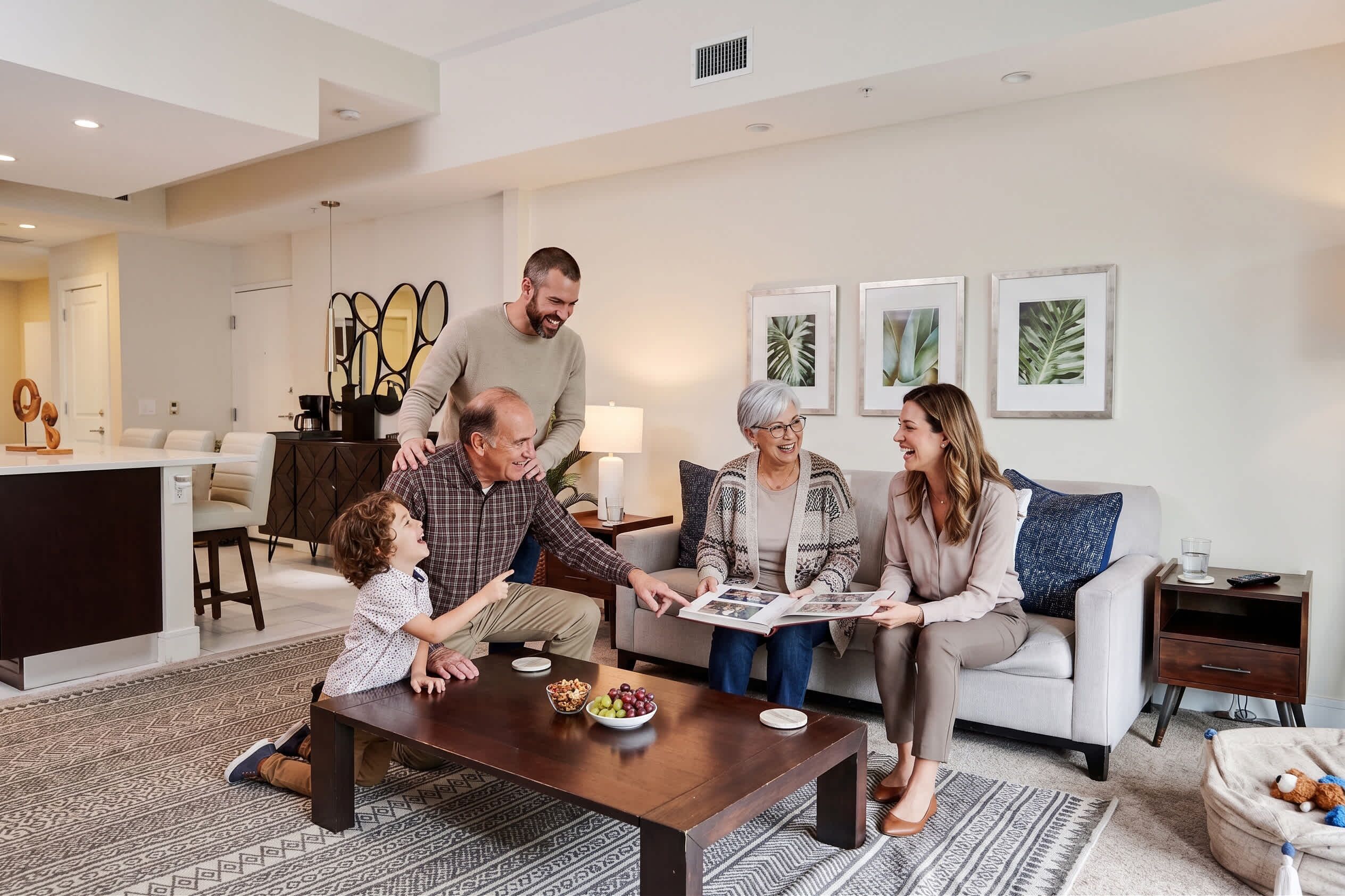A family in a modern living room with a dining table, a sofa, and a coffee table. - Villa Vista by VIAC - 2 Story w/ 3Bdrms & Golf View (Doral)