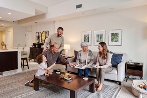 A family in a modern living room with a dining table, a sofa, and a coffee table. - Villa Vista by VIAC - 2 Story w/ 3Bdrms & Golf View (Doral)
