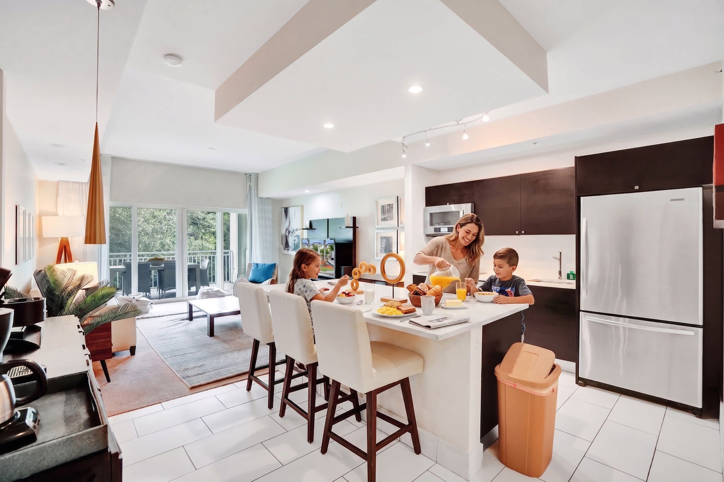A modern kitchen with a central island, stainless steel appliances, and a dining area with a view.