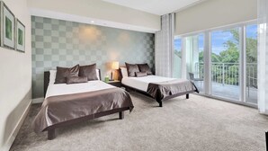 Ein Hotelzimmer mit zwei Betten, einem großen Fenster und einem Balkon, sowie einer Wandgestaltung mit Schachbrettmuster.