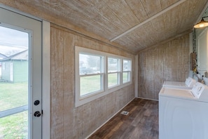 Une buanderie avec des murs en bois, de grandes fenêtres et un lave-linge.