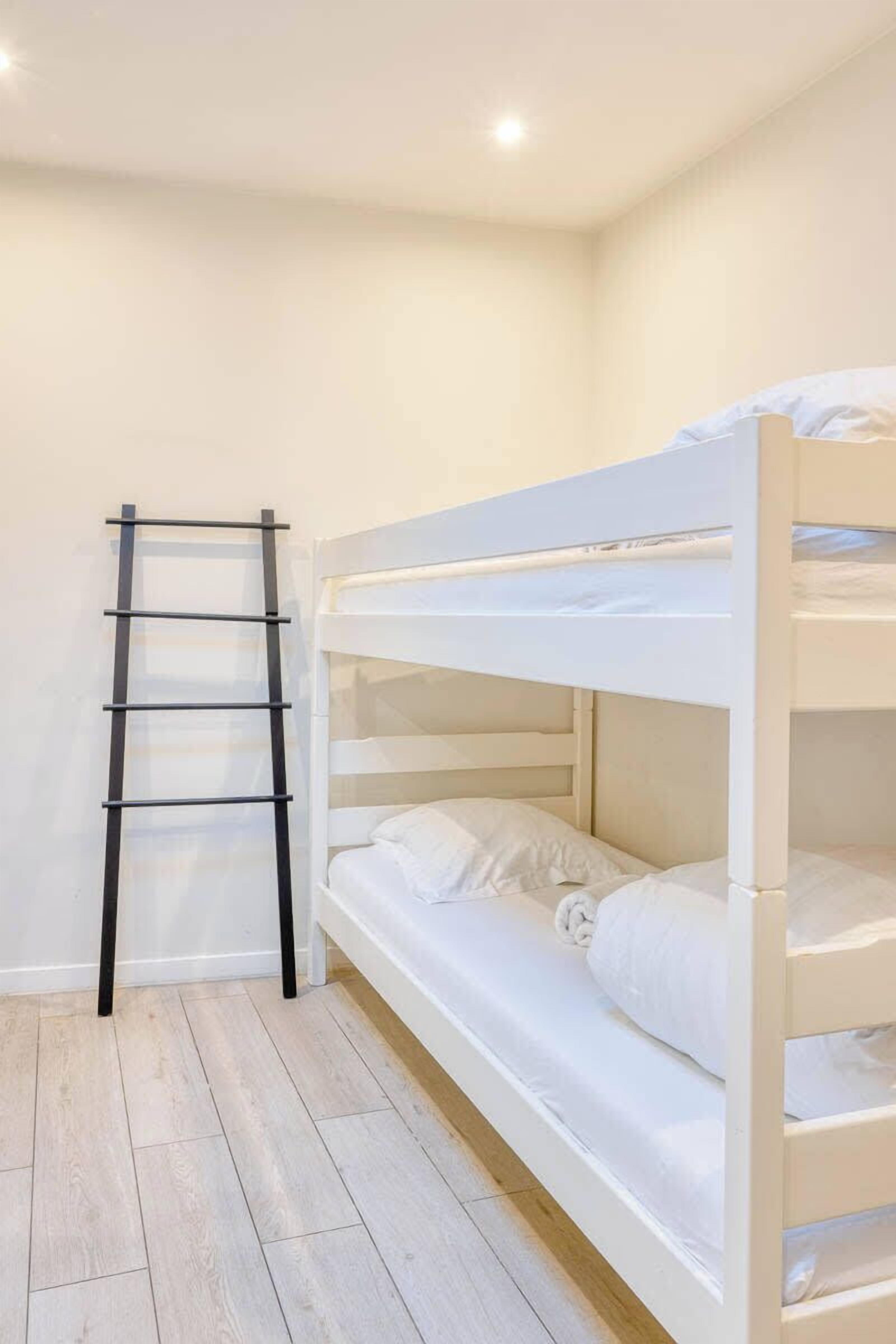 Un letto a castello con biancheria bianca e una scala nera.