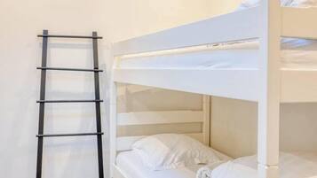 Un letto a castello con biancheria bianca e una scala nera.