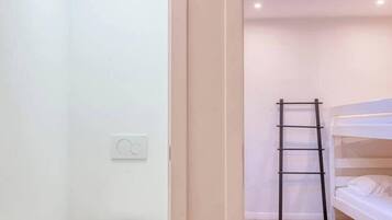 Een kleine, moderne kamer met een stapelbed, dakraam en een apart toilet.