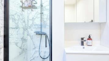 Un bagno moderno con doccia vetro, lavandino bianco e specchio soprastante.