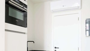 Eine moderne Küche mit weißen Schränken, einem Backofen, einer Spüle und einer Tür mit Griff.