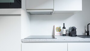 Moderni keittiö, jossa on valkoiset kaapit, työtaso, kahvinkeitin, Rocin-pullo ja pakkaus Rocin-makua.